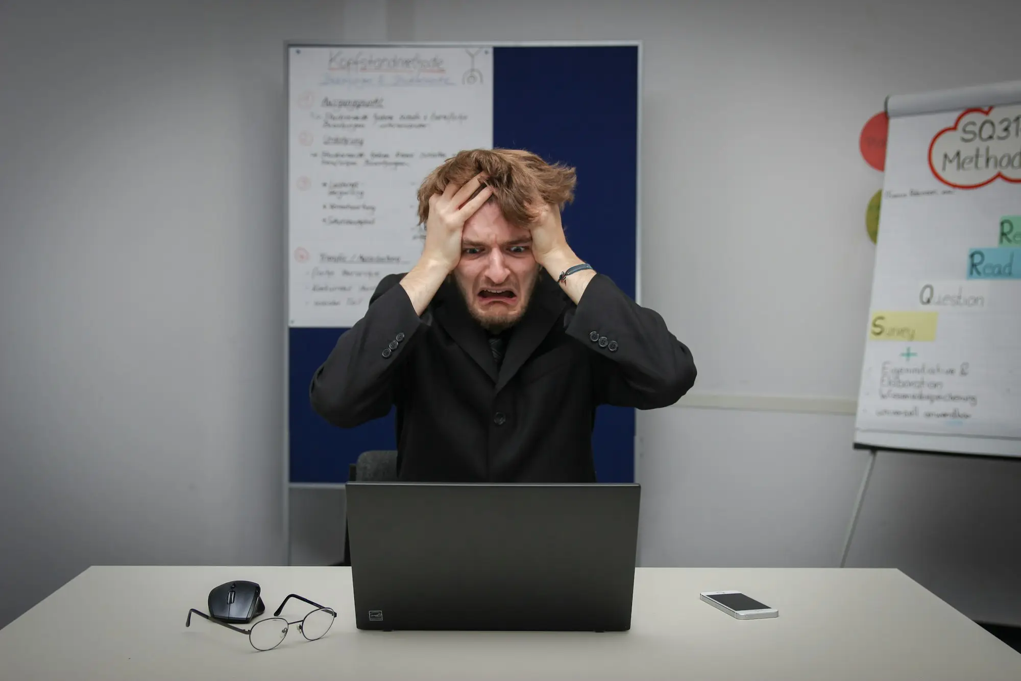 Business owner with his head in his hands at a laptop after seeing an IRD default assessment estimate